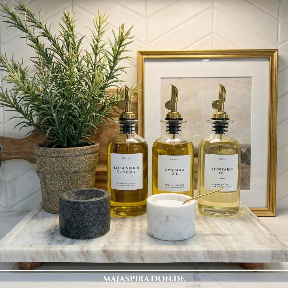 Küchendeko auf Steintablett mit Glasflaschen für Öle und kleiner Kräutertopf