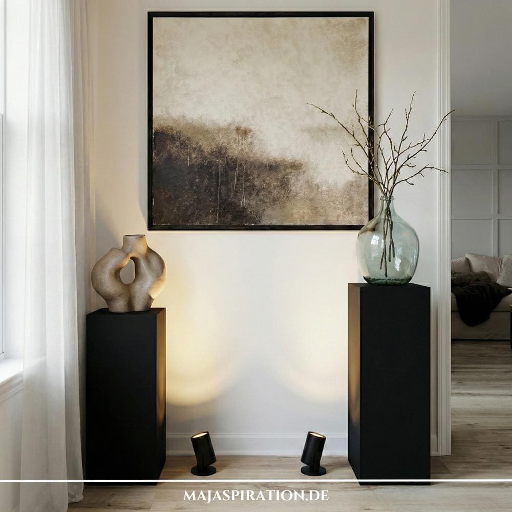Schwarze Podestsäulen vor abstraktem Wandbild als Styling Idee für leere Raumecken