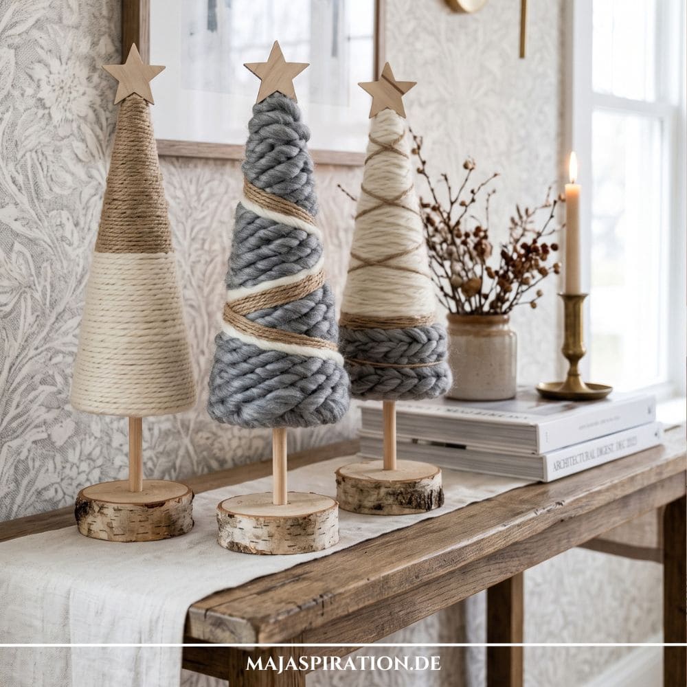 Kuschelige DIY Weihnachtsb&auml;ume aus grauer und wei&szlig;er Wolle, garniert mit Juteschnur auf Baumscheiben-Standf&uuml;&szlig;en, als Idee f&uuml;r nat&uuml;rliche DIY Weihnachtsdeko ohne Plastik.